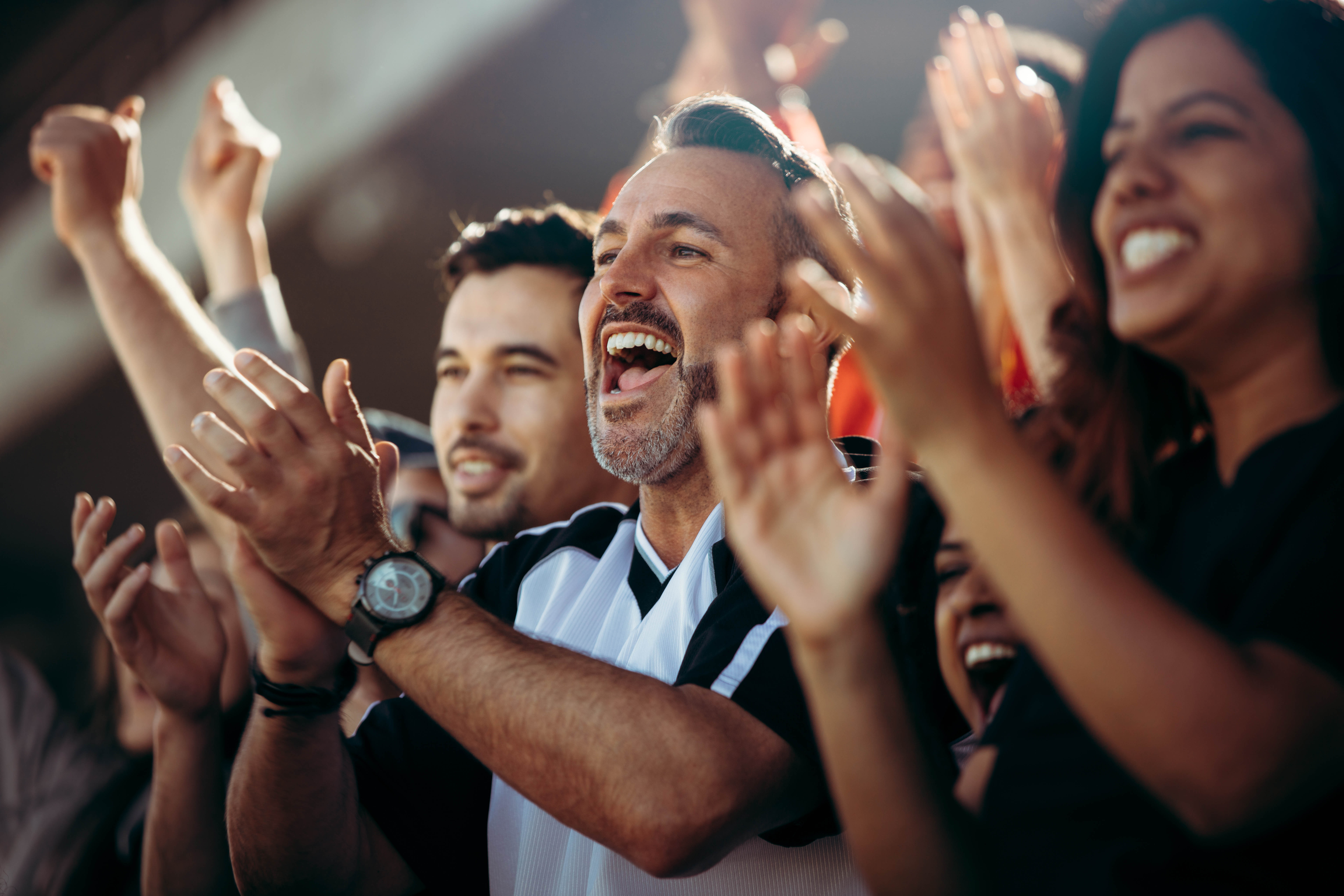 Diverse crowd of people cheering and applauding at a sports event